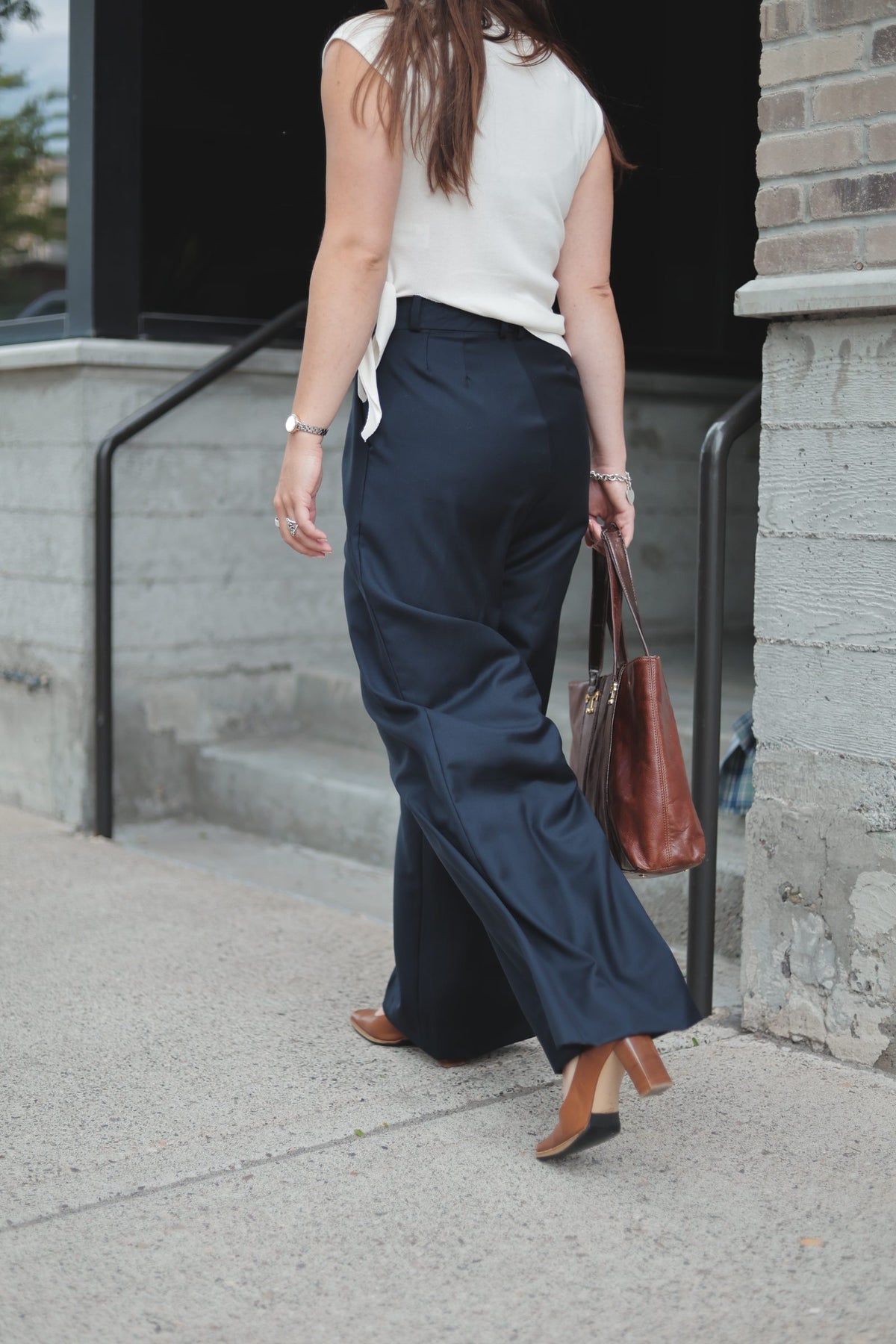A woman walking up concrete steps in wide-leg wool trousers