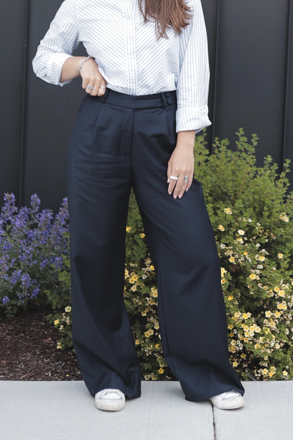 Front view of the navy wool trouser showing the buttoned waistband tab, pleats and full wide leg
